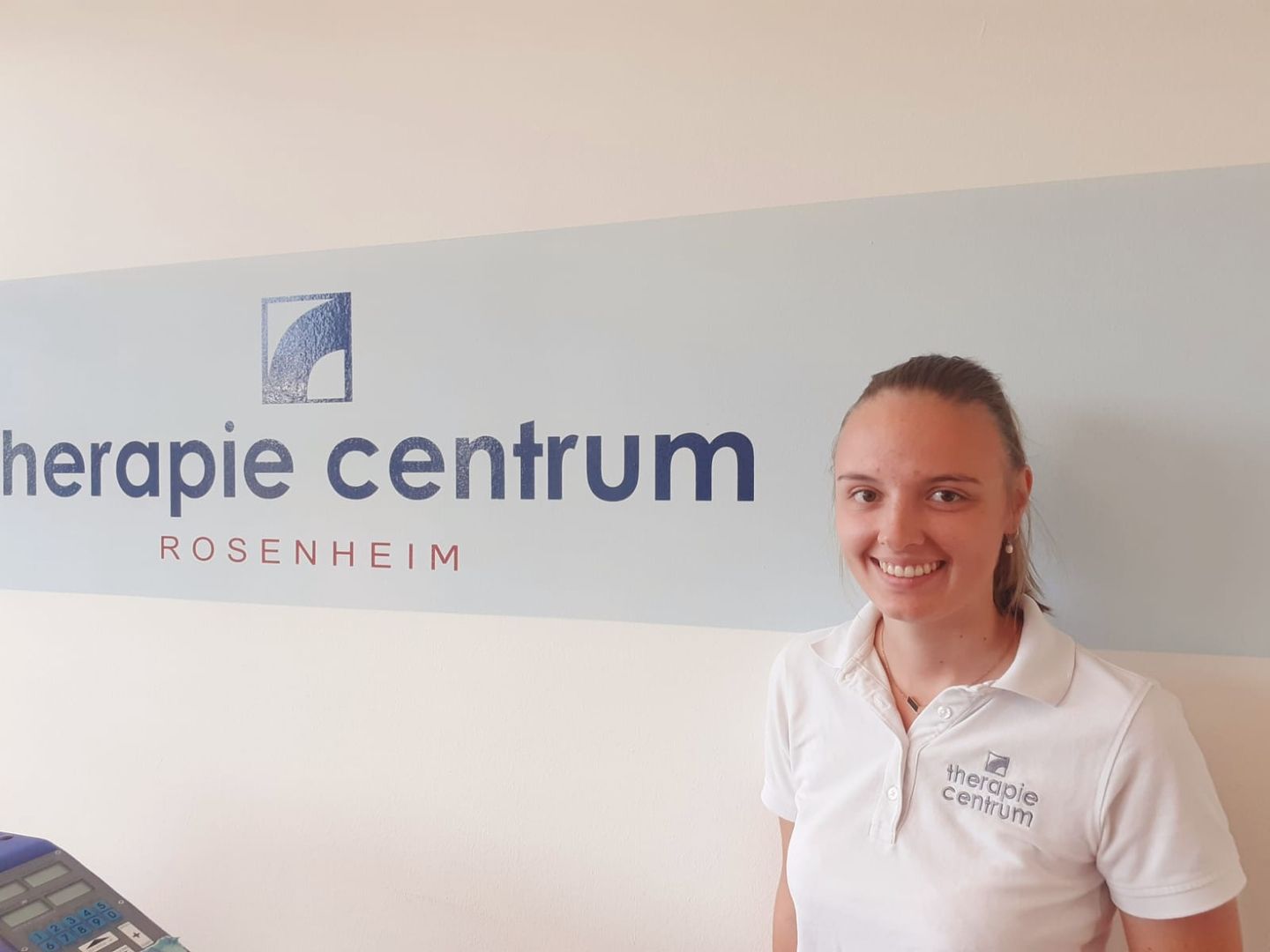 Selina steht vor einer Wand mit dem Firmenlogo